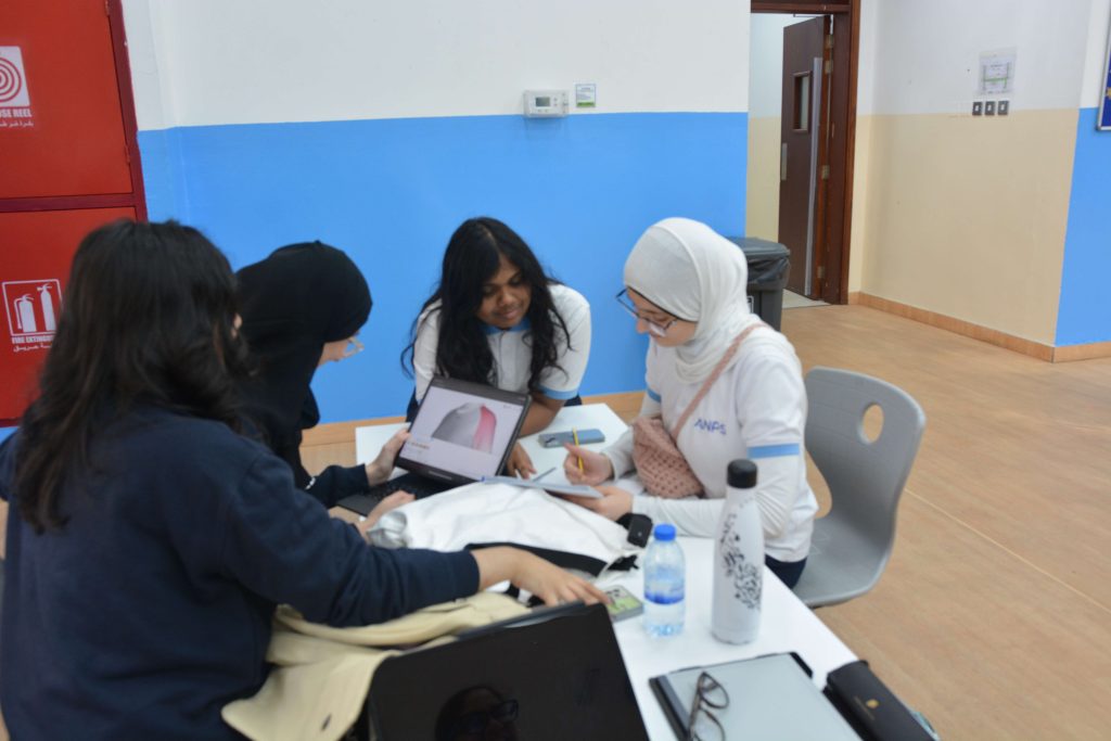 ANPS Middle School students working together around a table beside a classroom display board