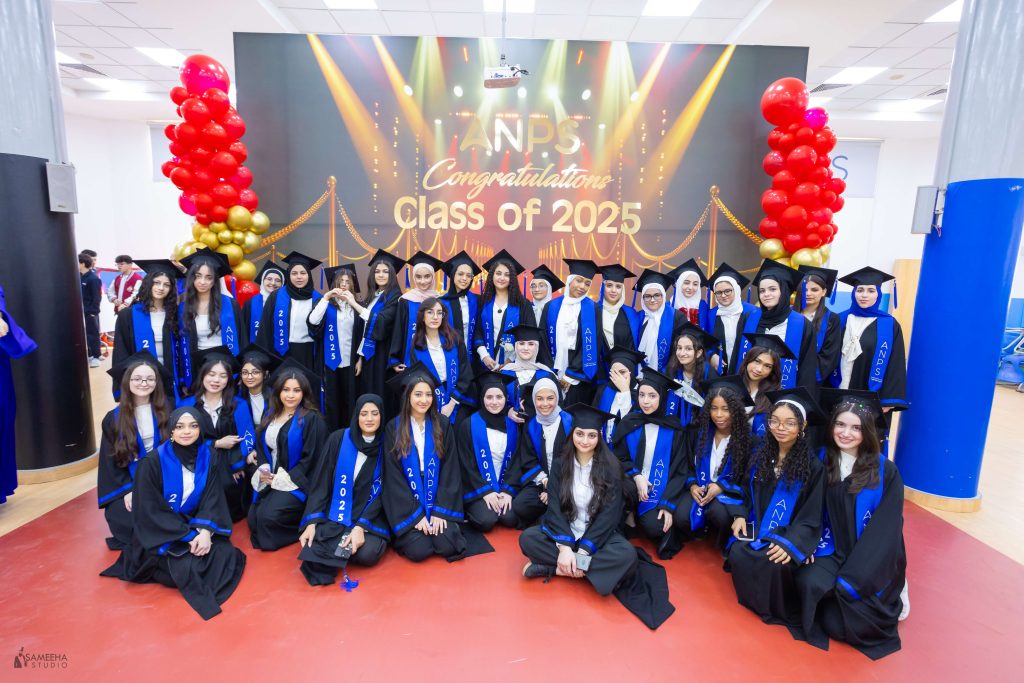 ANPS Class of 2025 graduates gathered for a group portrait in front of a congratulations backdrop with balloons
