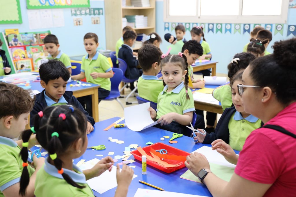 ANPS Kindergarten children working on a cutting and gluing activity with their teacher